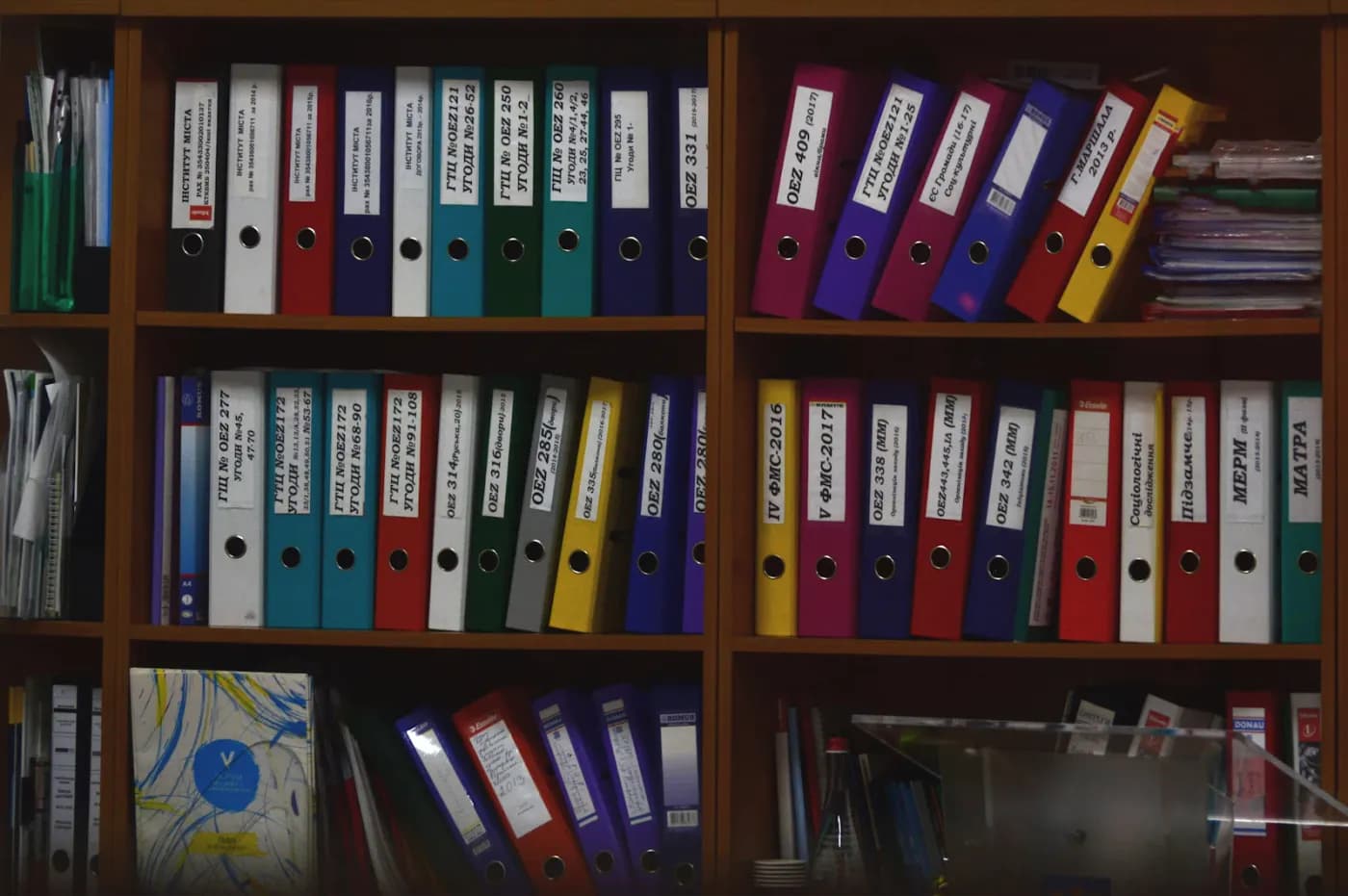 Rows of labeled compliance binders and folders organized on office shelves